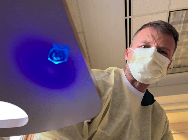 An infection prevention expert using a black light to check the underside of a table in a patient room.