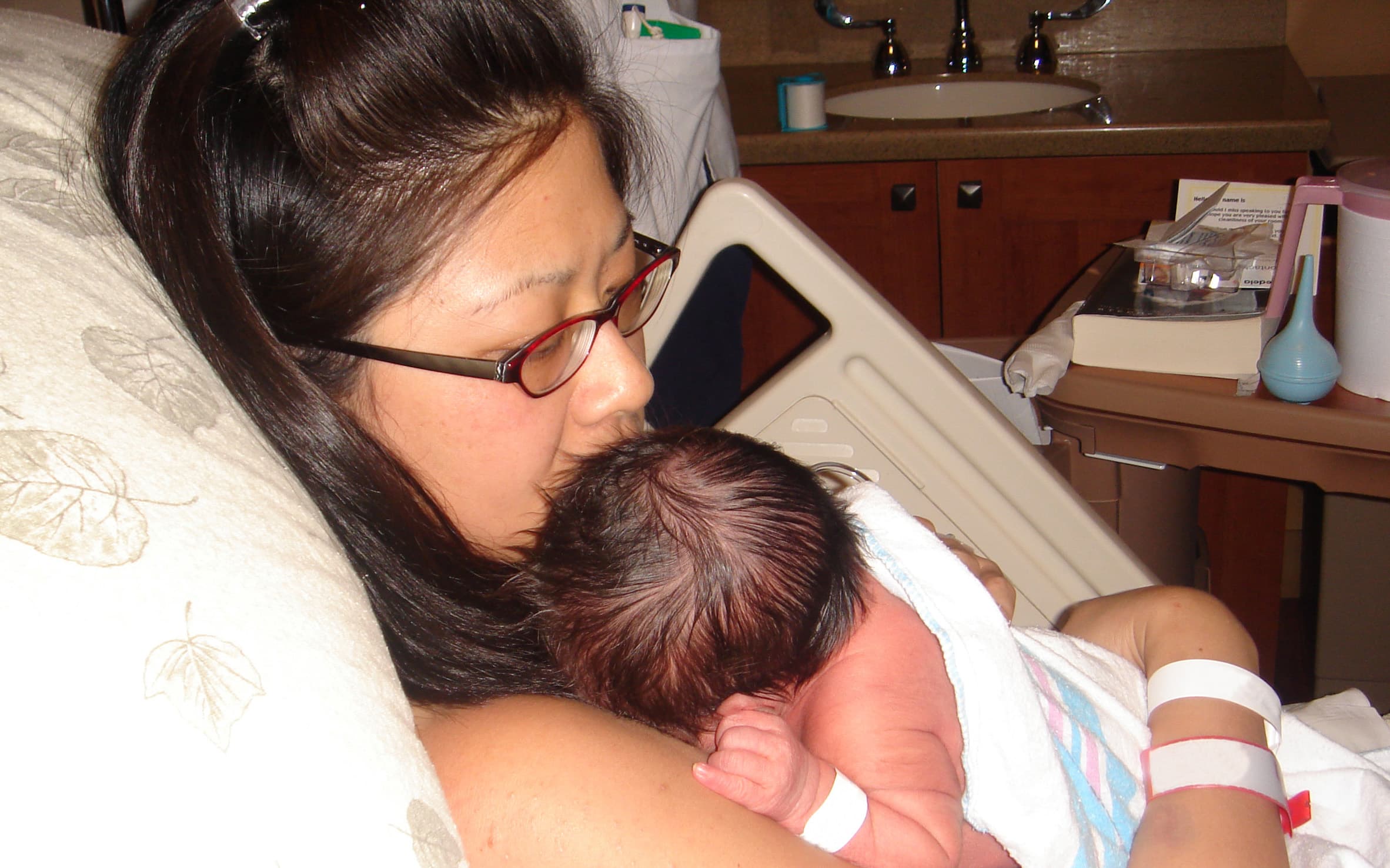 A mother holds her newborn baby in a hospital room.