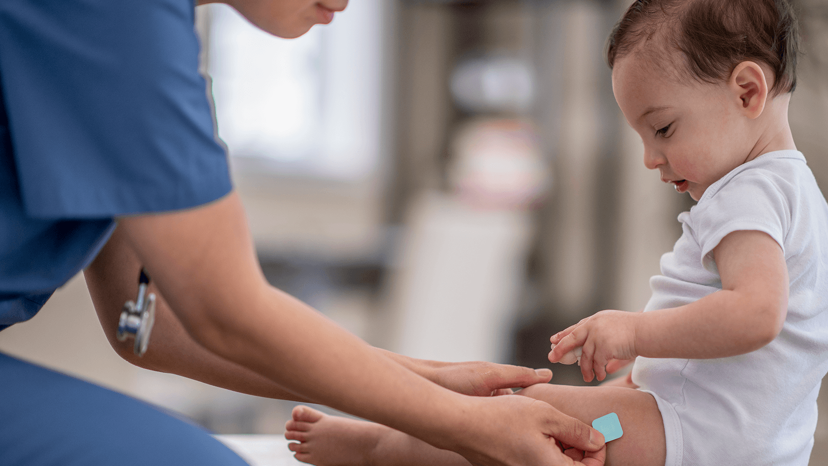 A healthcare worker applying a small bandage to the upper arm of an older adult woman after a vaccination.